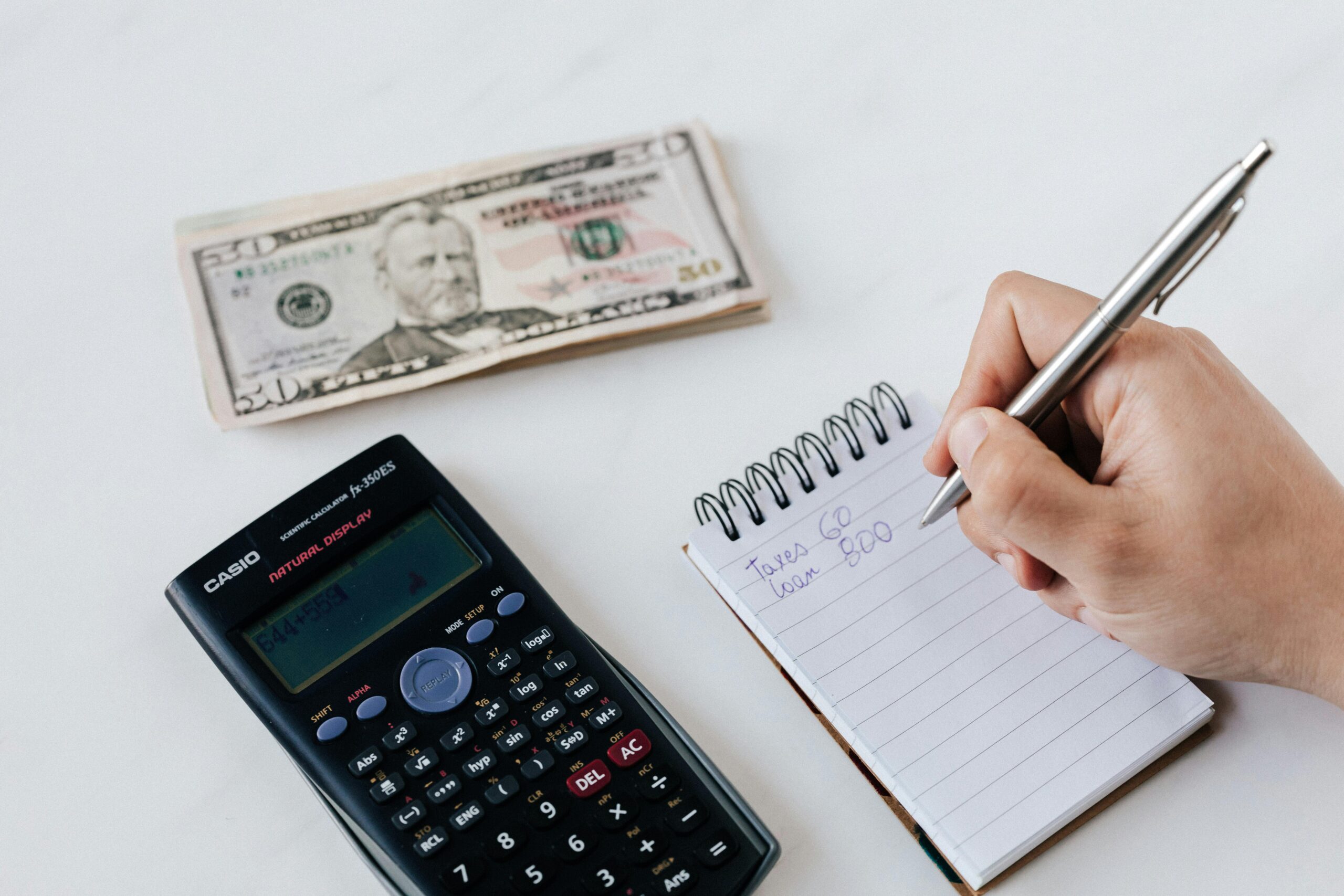 Detailed view of financial planning with a calculator and notebook, illustrating budget optimization techniques.