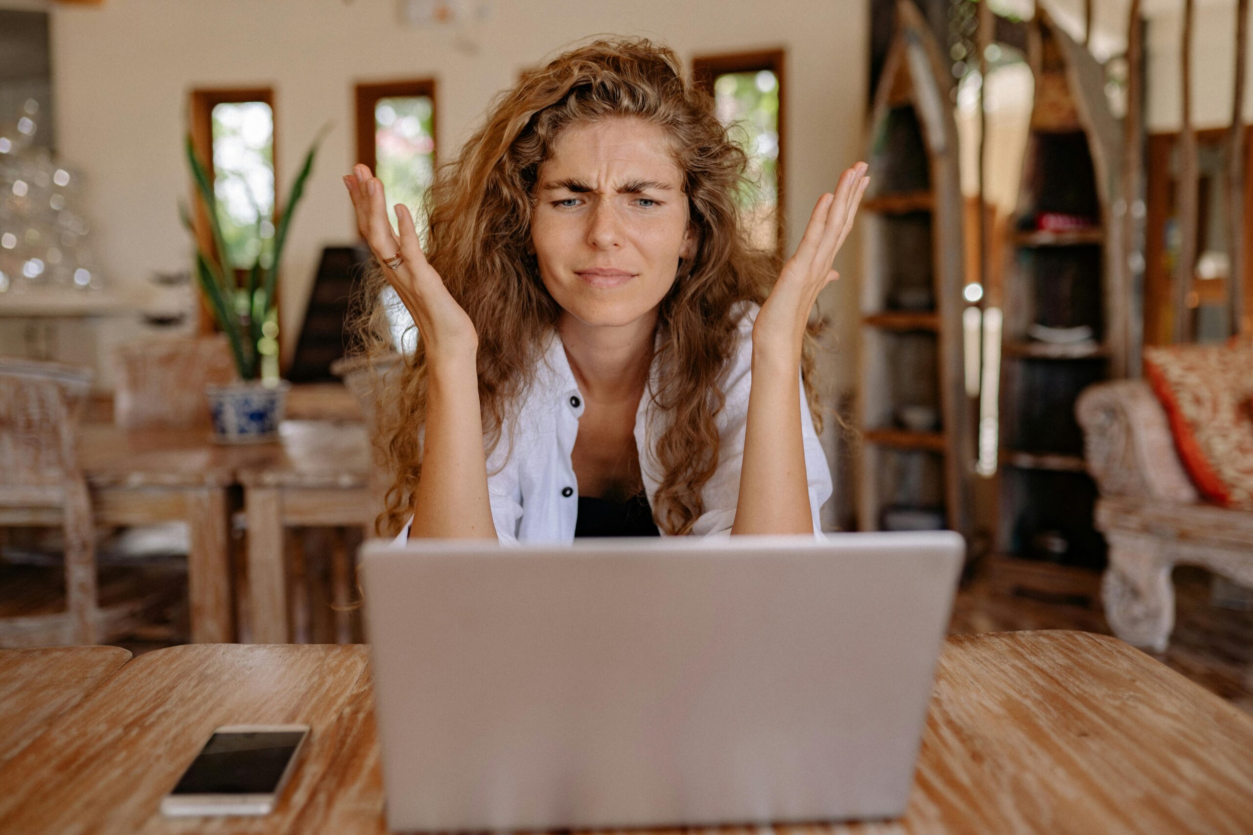 Woman appears frustrated working on a laptop, a scenario where marketing outsourcing could provide needed support.