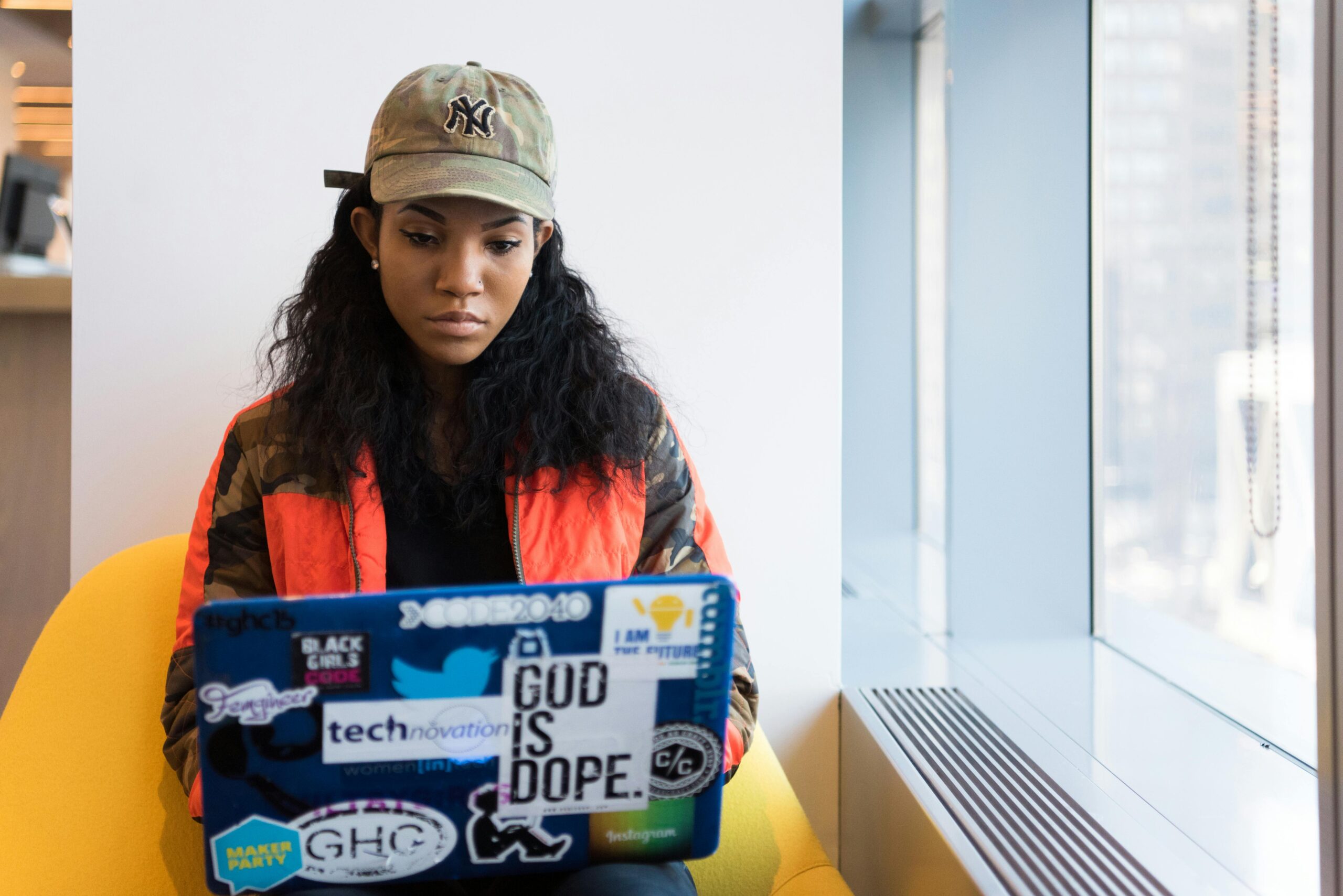 Remote employee working on a laptop with a sticker-covered lid.