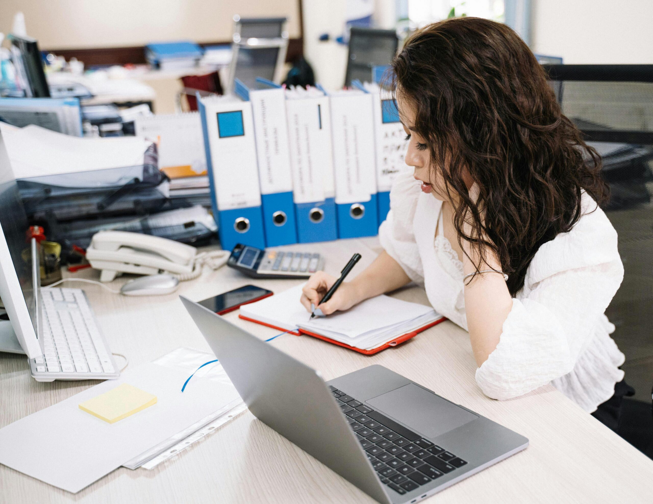 Woman working on financial documents in an office, demonstrating outsourcing in accounting.