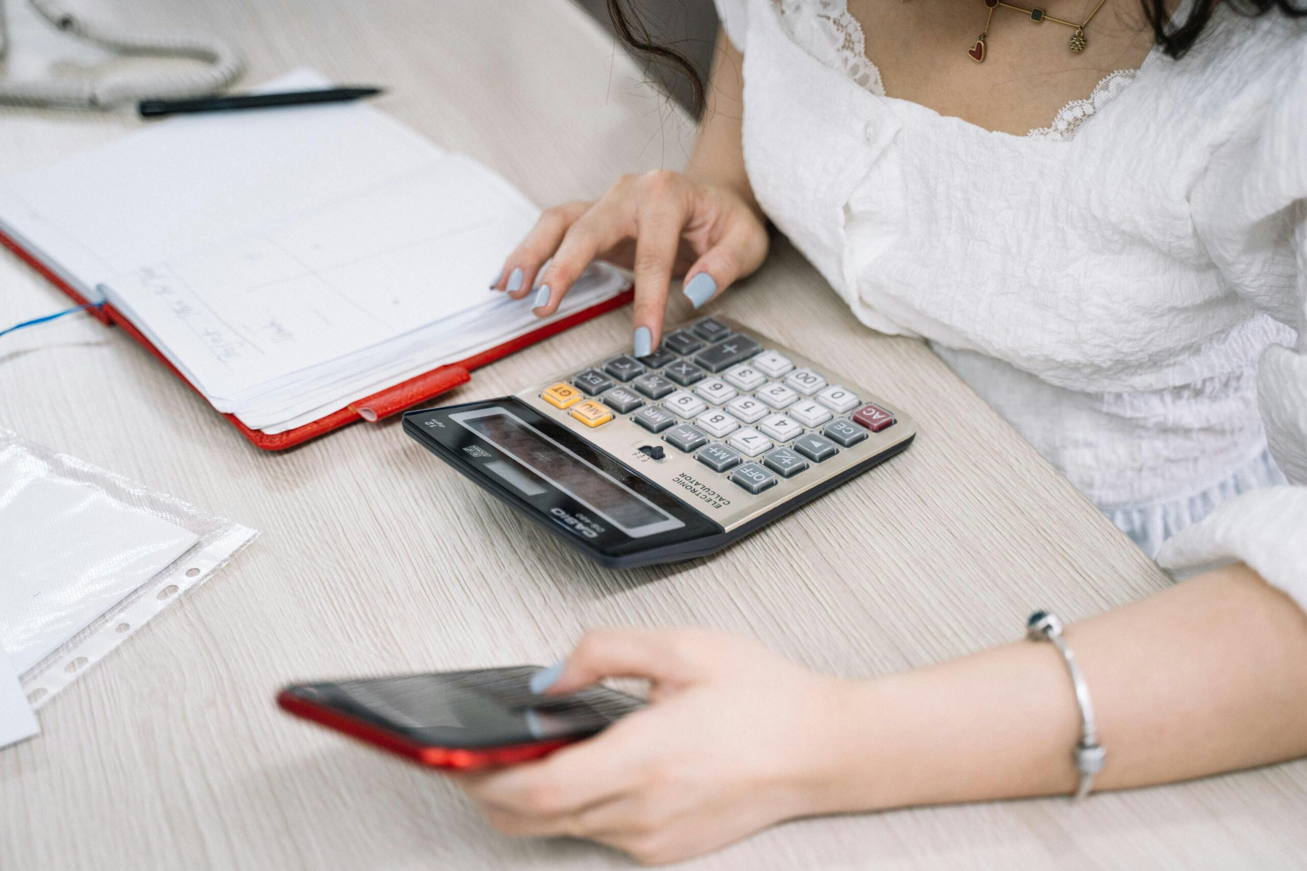 A woman using a calculator and smartphone.