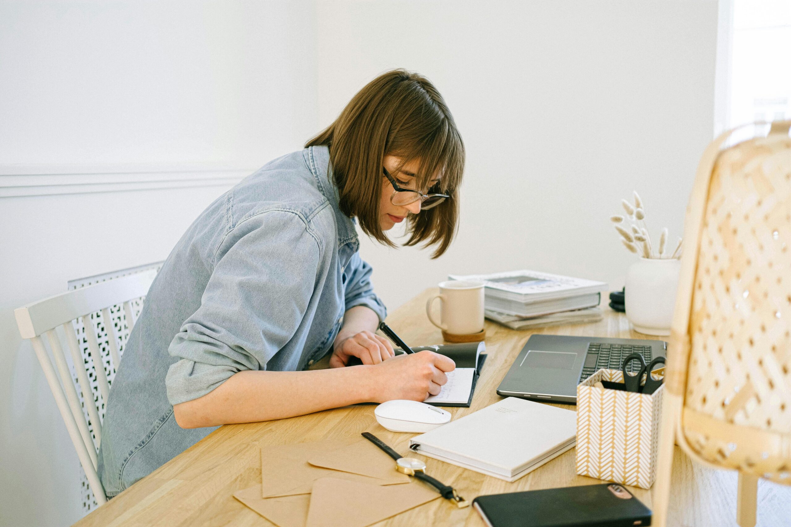 Woman writing notes at her desk.