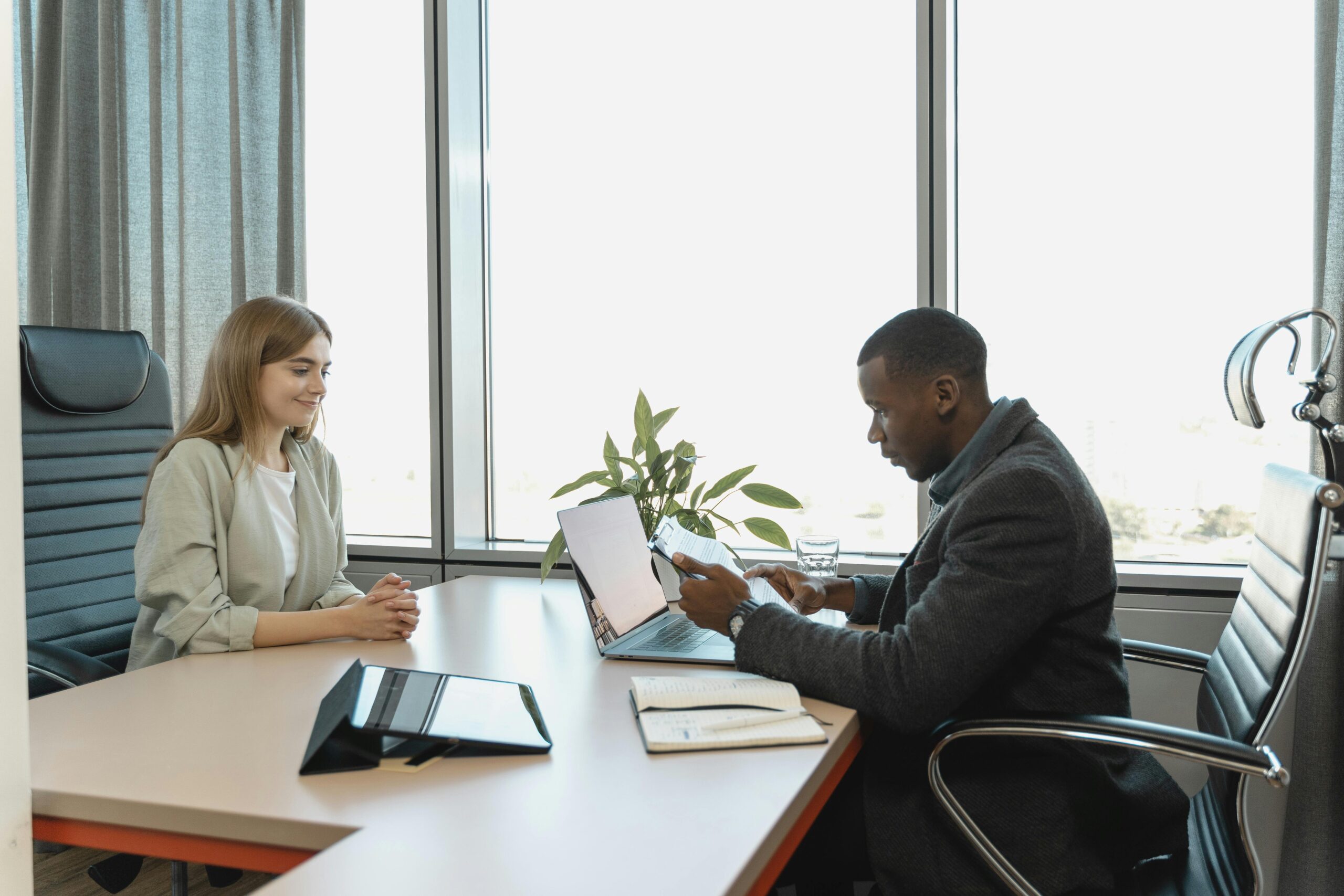 A man and woman sitting across a table during an interview.