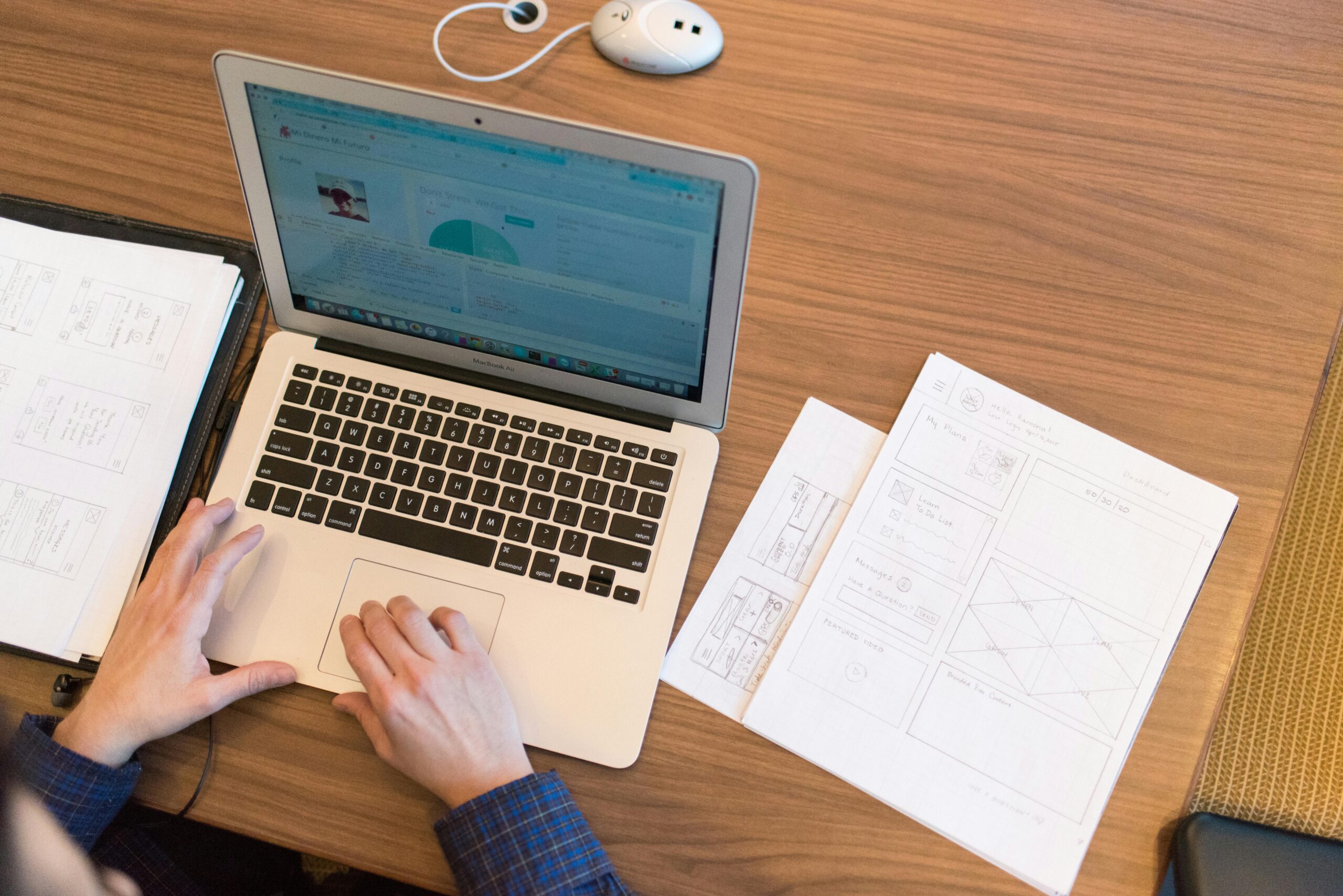 Employee working on a laptop with an onboarding document for new hires beside them.