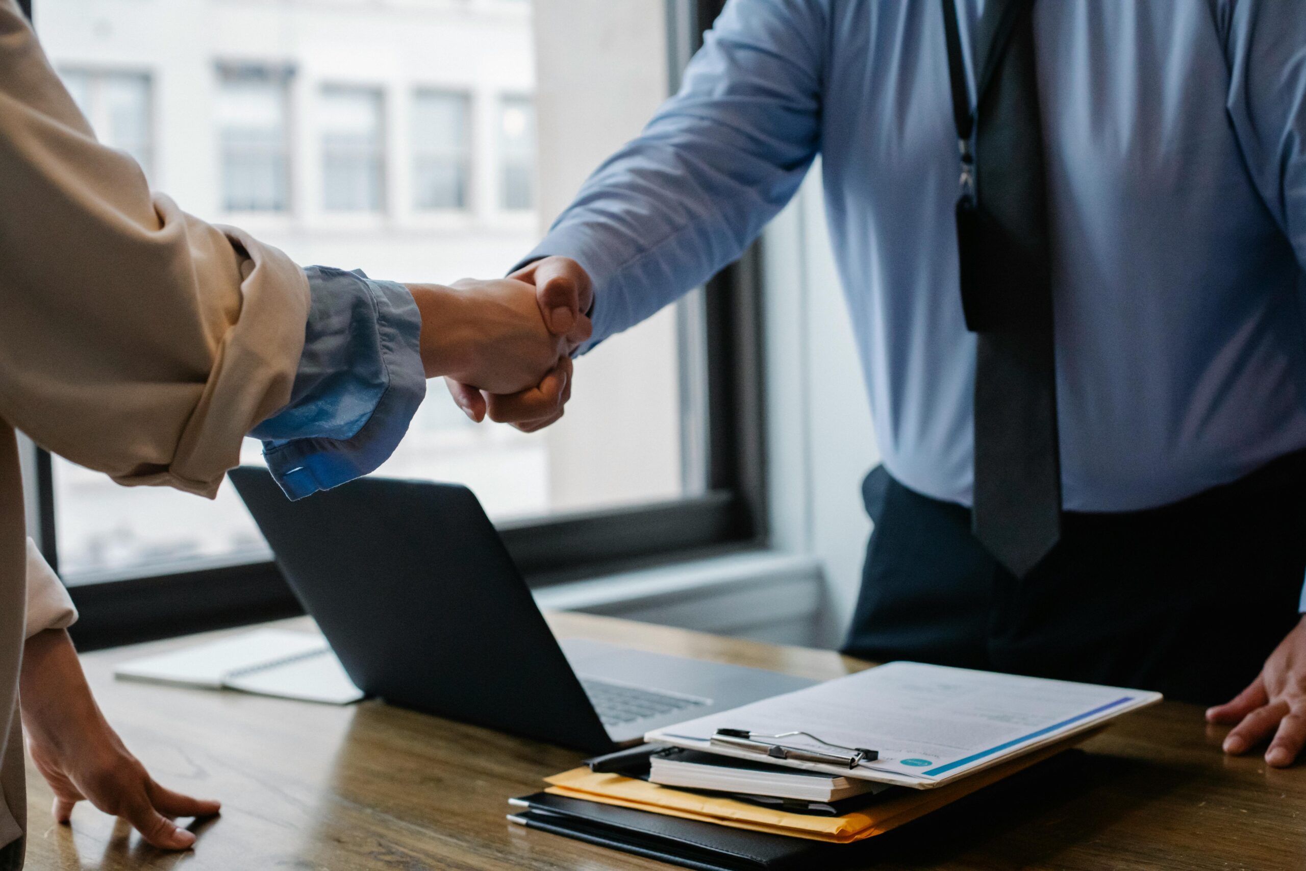 Two business professionals shaking hands after finalizing a contract for recruitment agency services.
