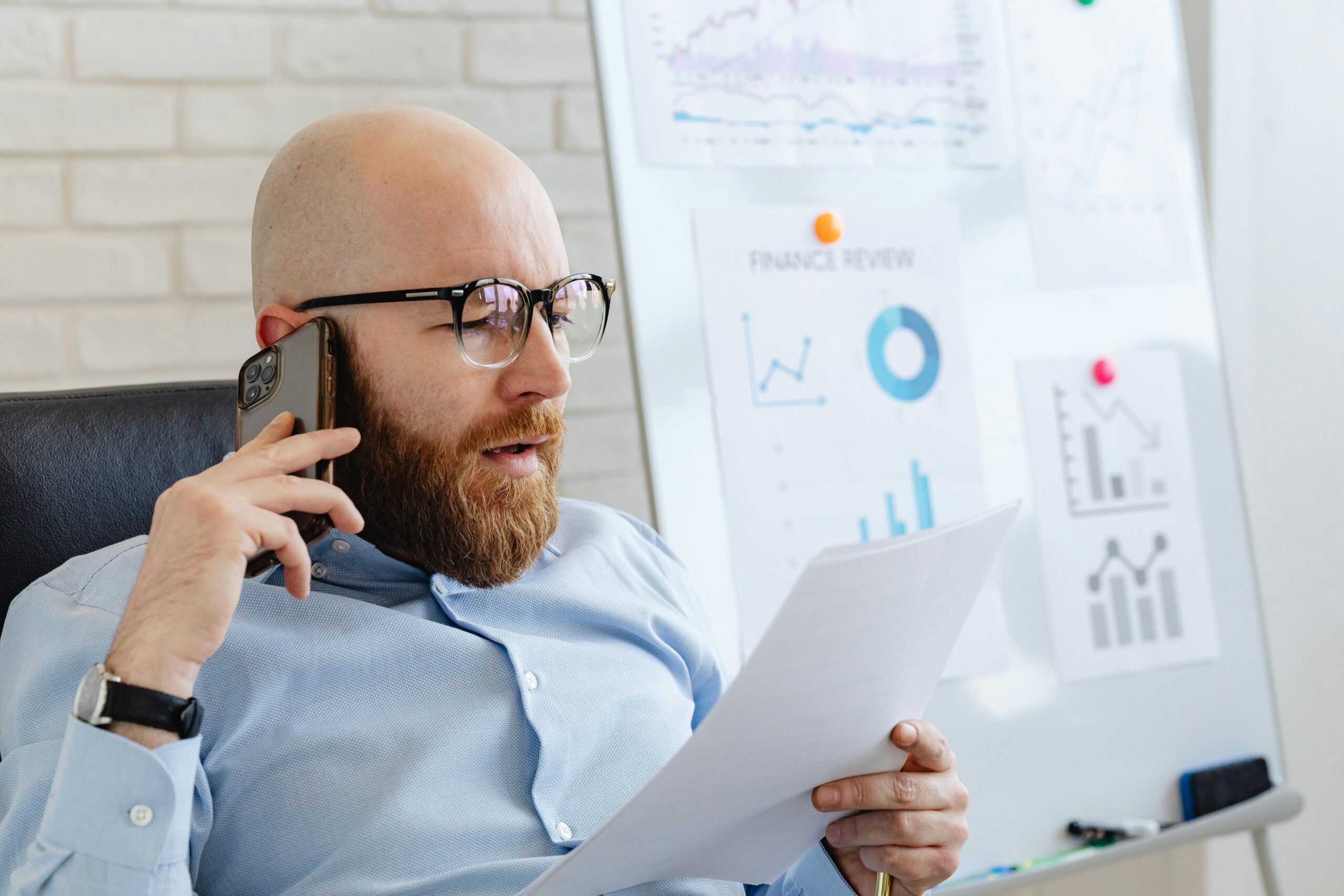 An IT assistant reviewing financial reports on a phone call.