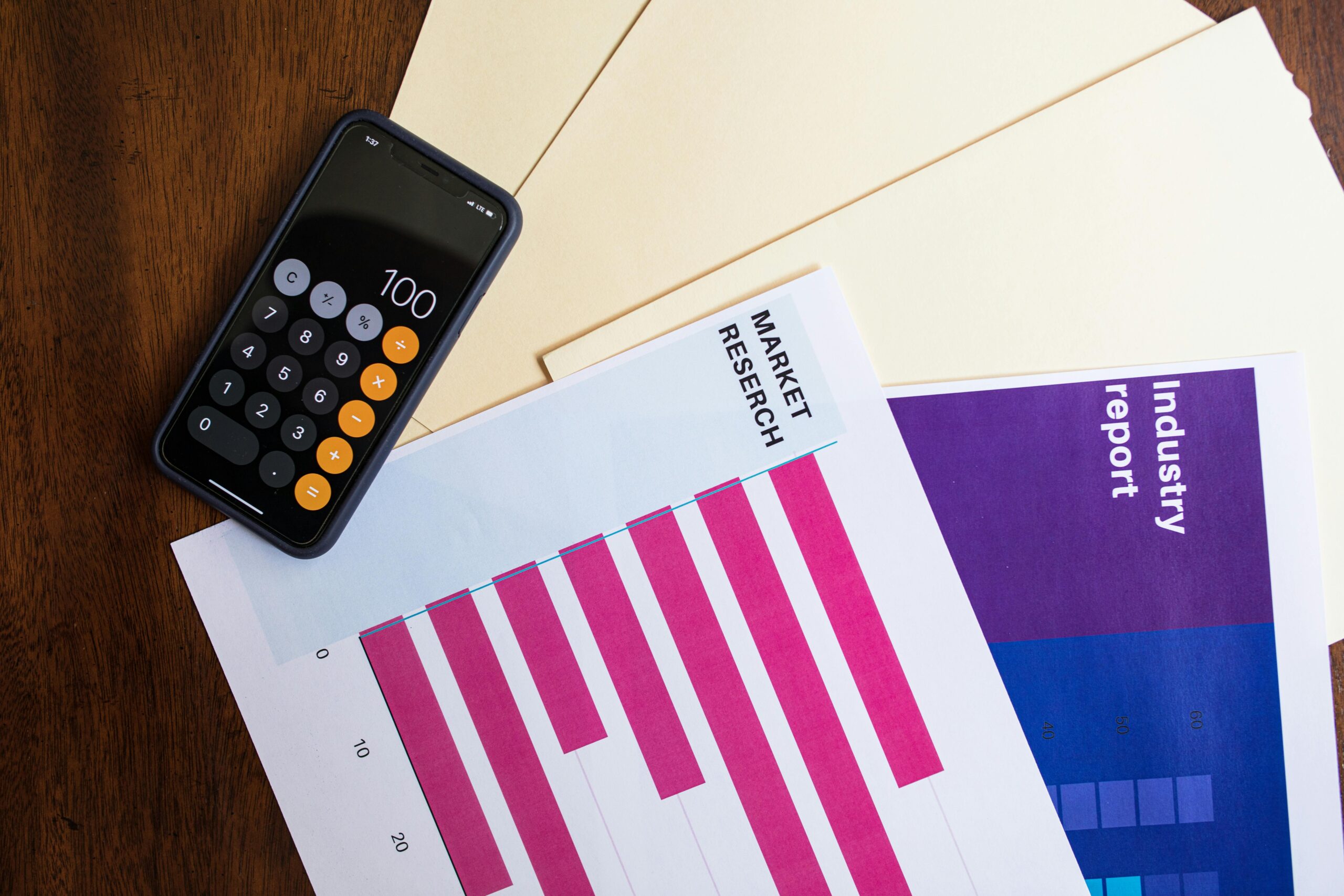 A market research report and a calculator on a desk, used for planning outsourced sales strategies.