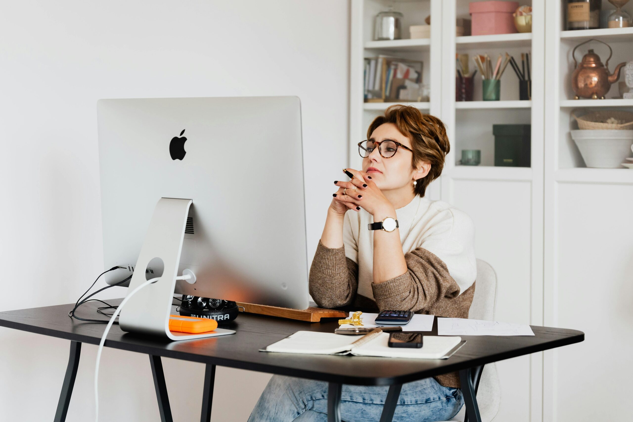 A person sitting at a desk with an iMac, appearing to read a termination of employment email on the screen.