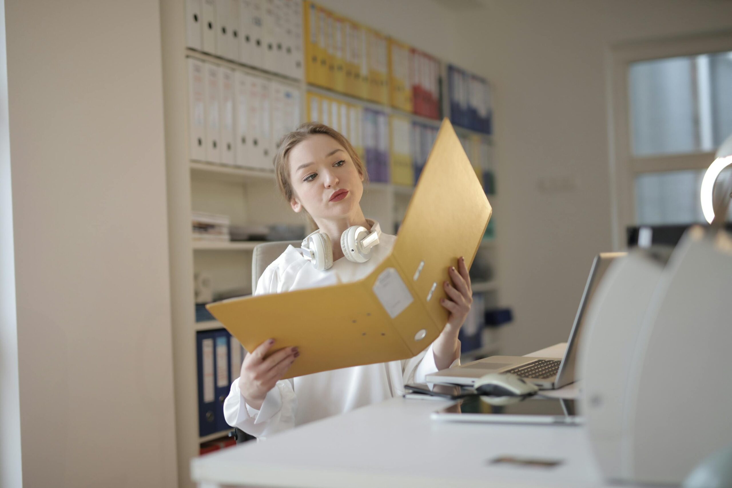 A woman in a professional office holding a yellow folder, symbolizing interview questions for staff accountants.