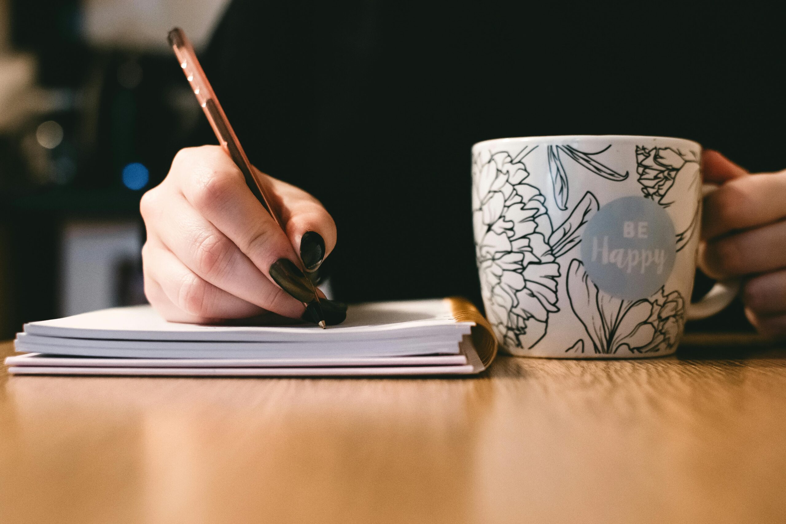 Hand holding a pen and a mug. Highlighting the potential of creative writers for hire.