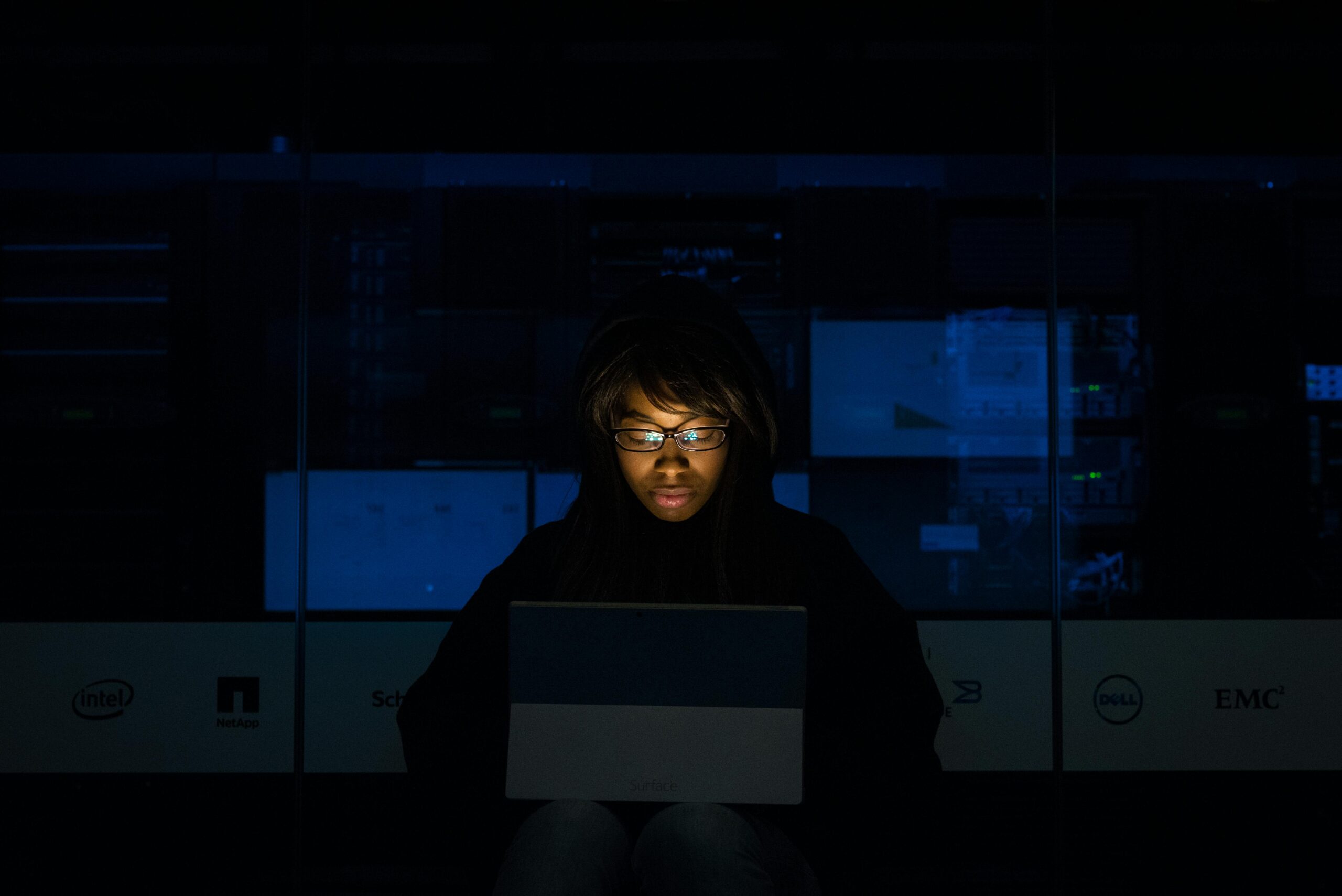 Person working on a laptop in a dark room. The challenges of managing remote developers.