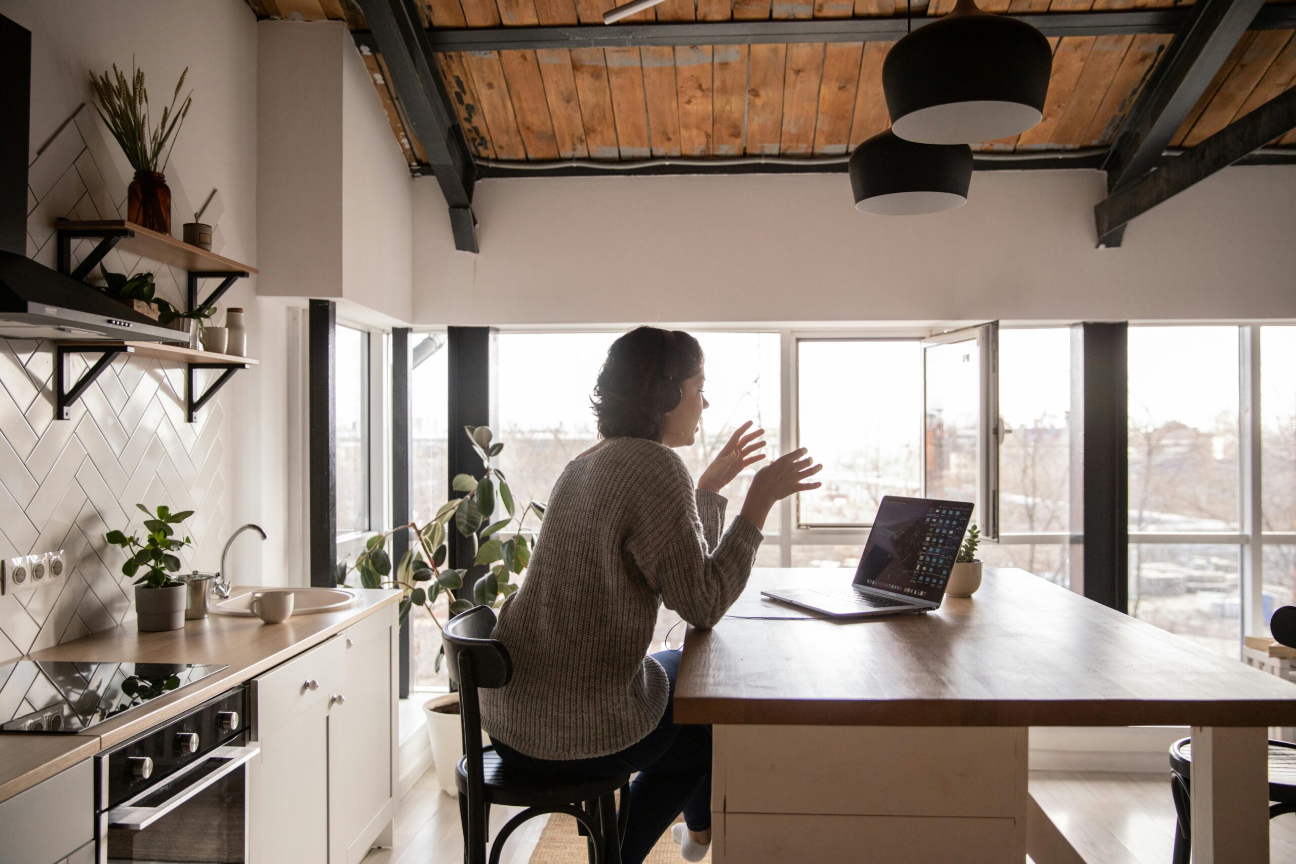 Woman working from home in a modern kitchen, showing the flexibility of hiring a virtual assistant.
