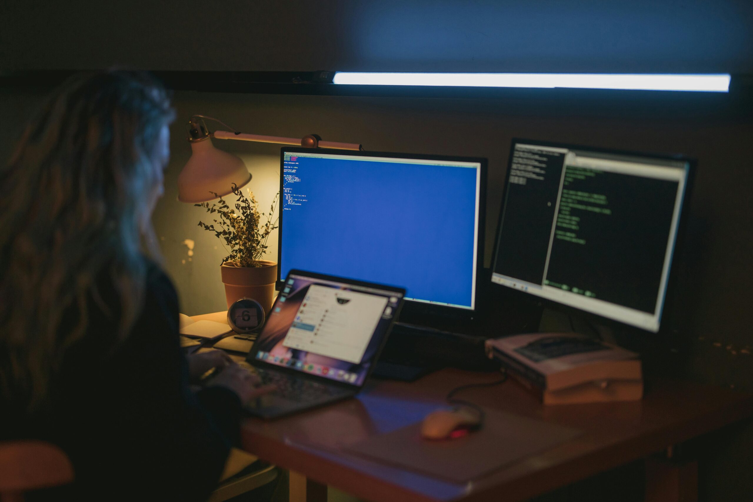 A person working late on multiple monitors, focusing on a remote data engineer job.