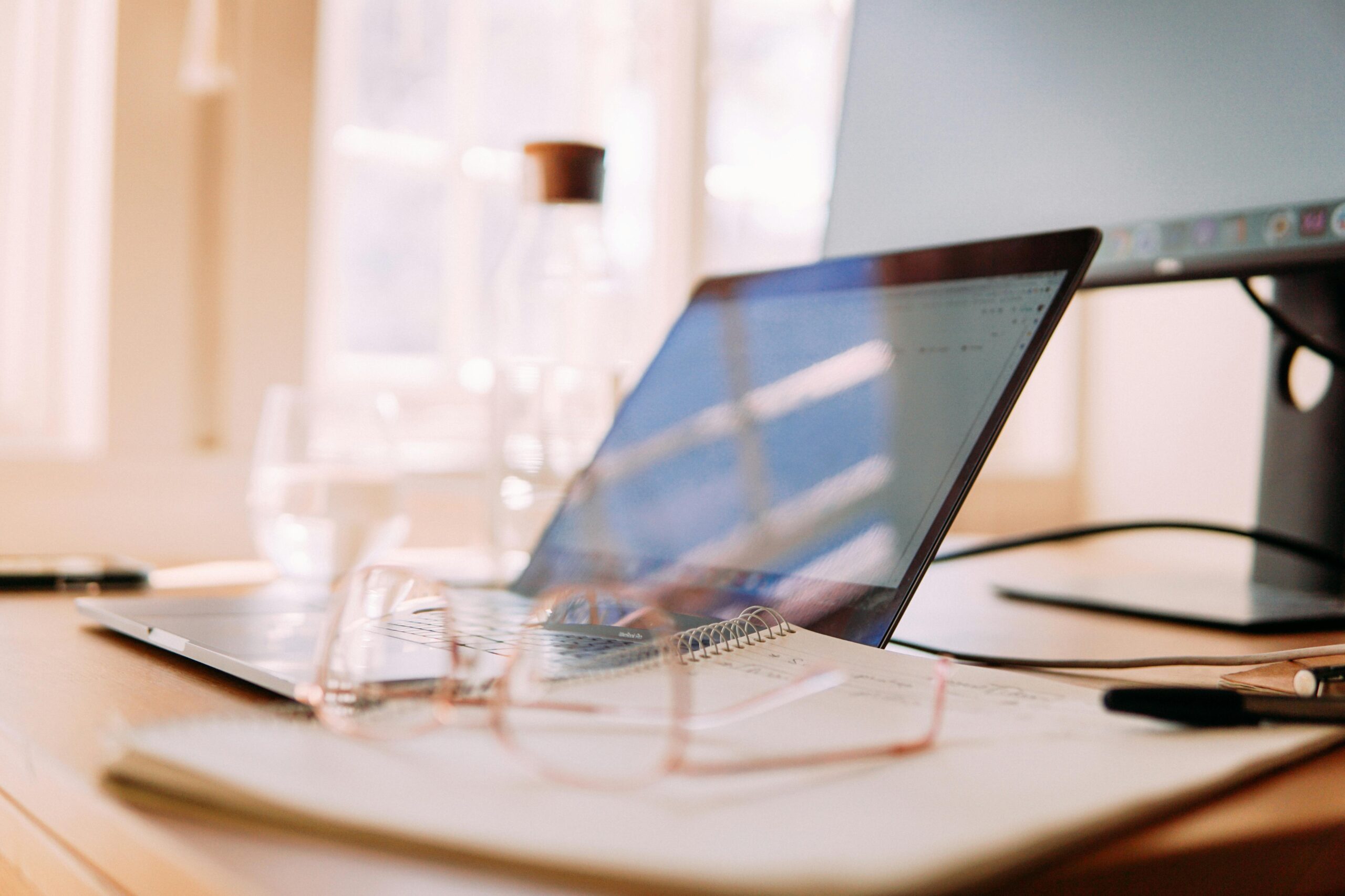 Outsource hiring concept with an open laptop on a desk displaying graphs, alongside a notepad and pen, suggesting a professional setting for remote recruitment.
