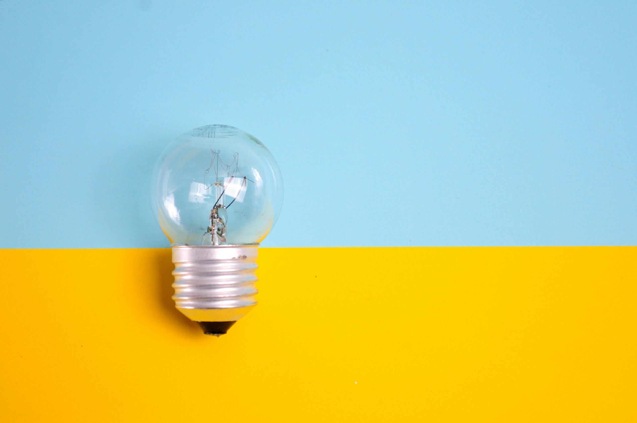 Offshore accountants concept with a clear light bulb on a split background of blue and yellow.