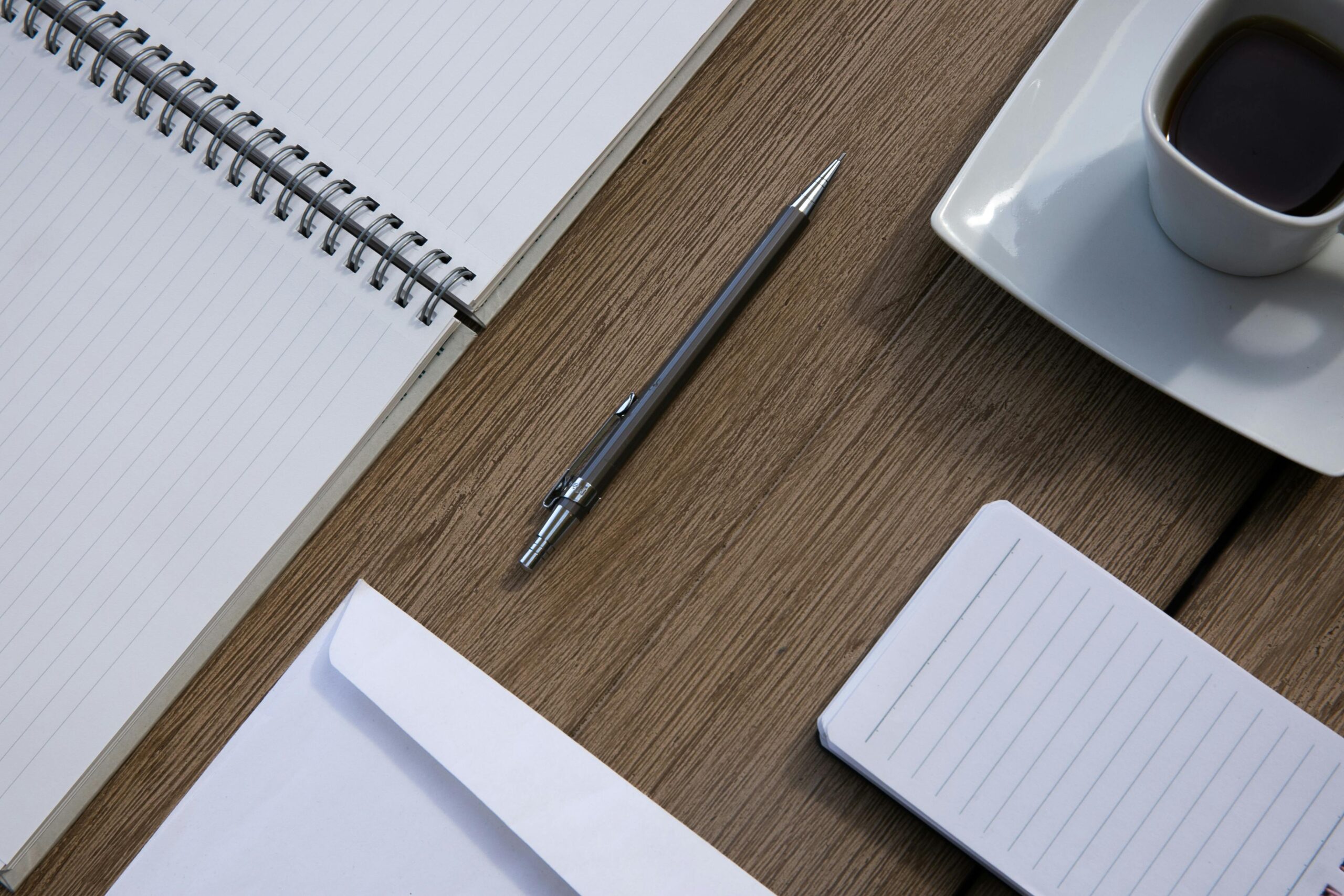 Organized desk with a notebook, pen, and coffee cup.
