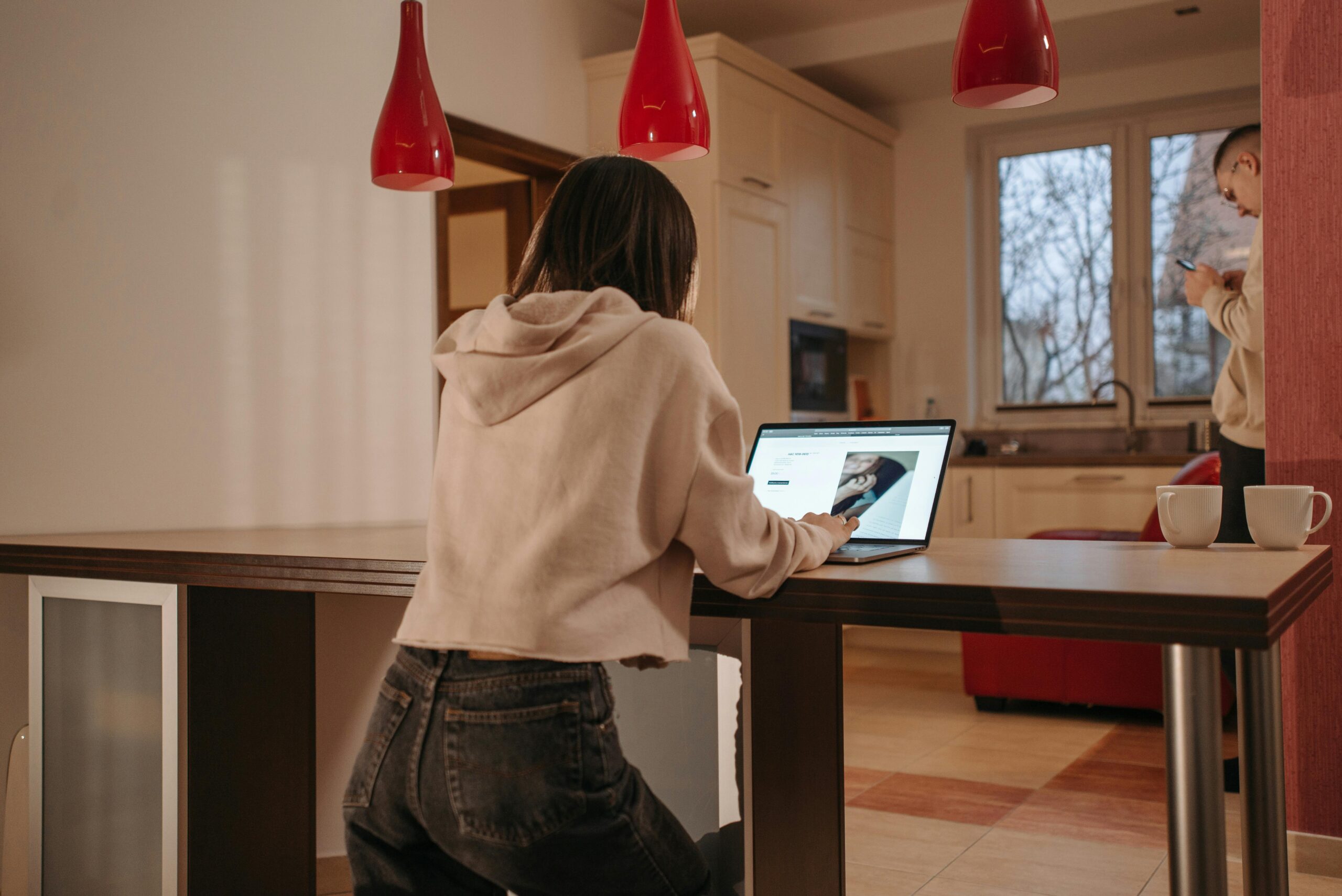 Woman working on a laptop in a cozy kitchen space.