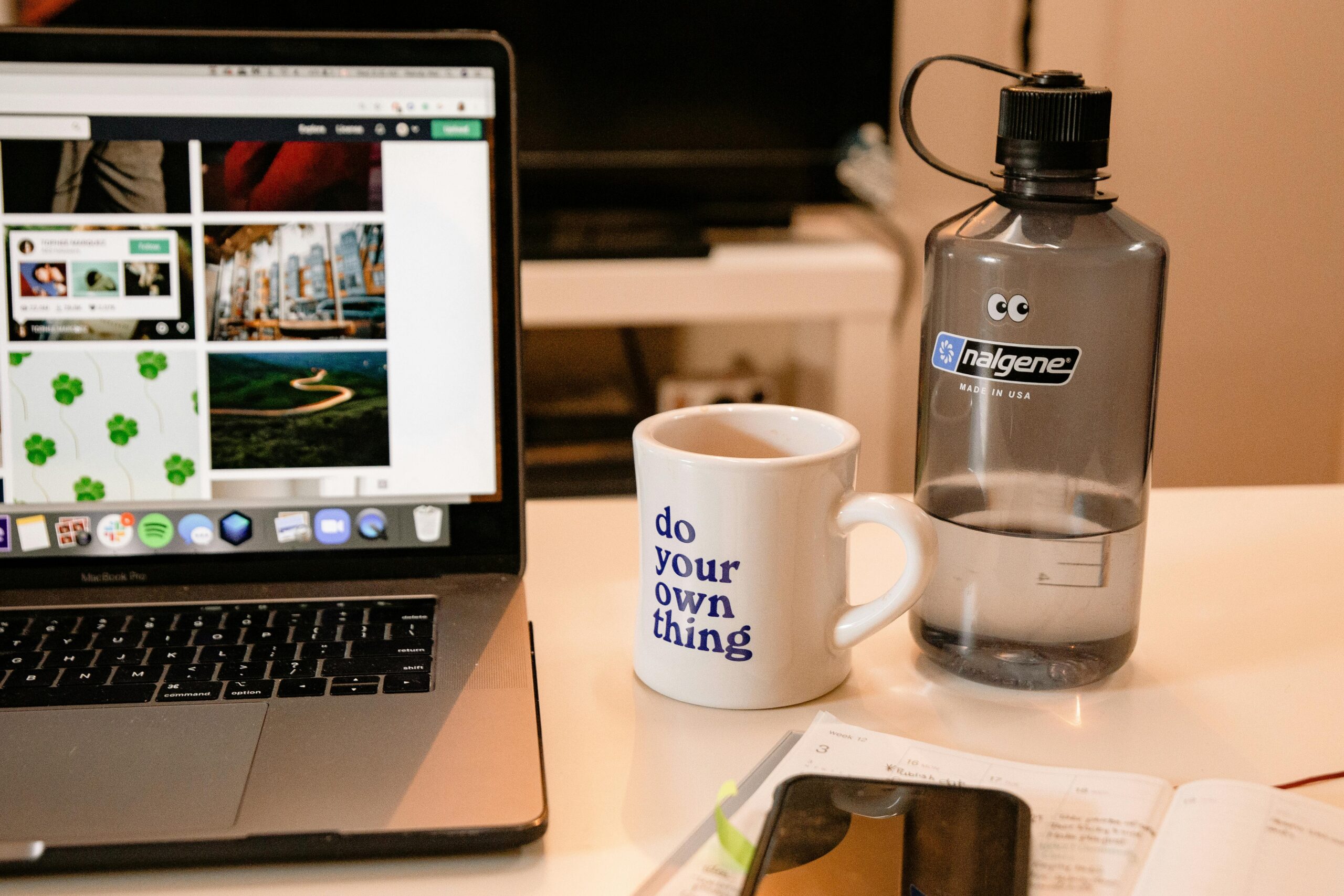 Laptop, coffee mug, and water bottle on a desk.