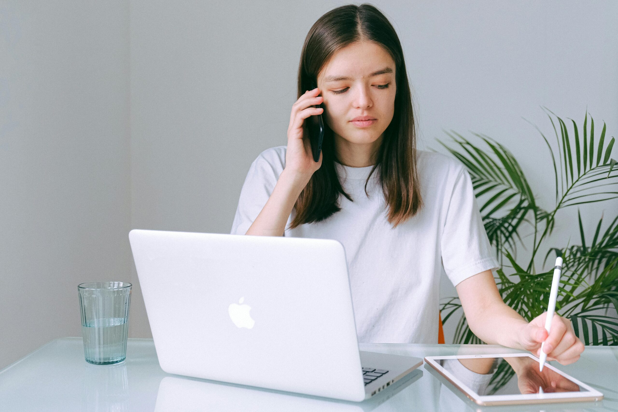 Woman on a phone call while using a laptop.