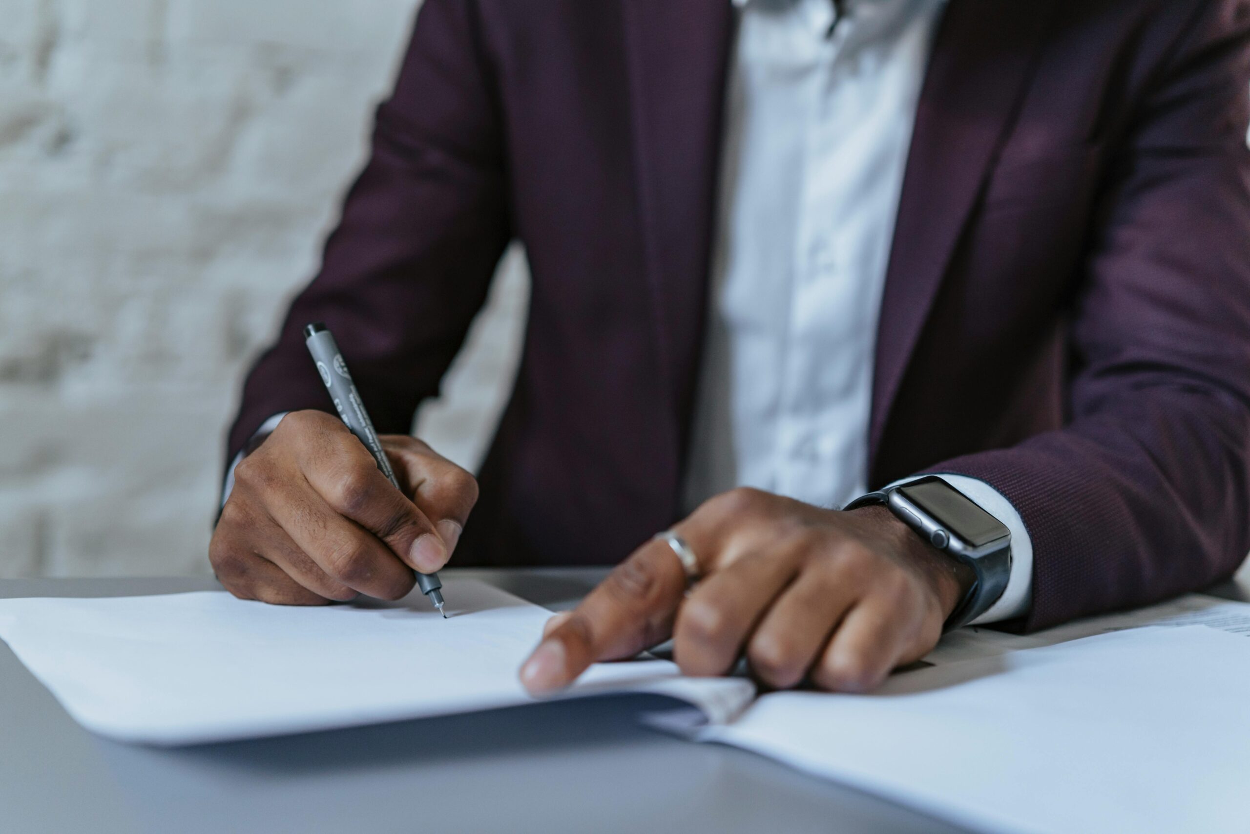Business professional signing a document, representing what is a contracted position.