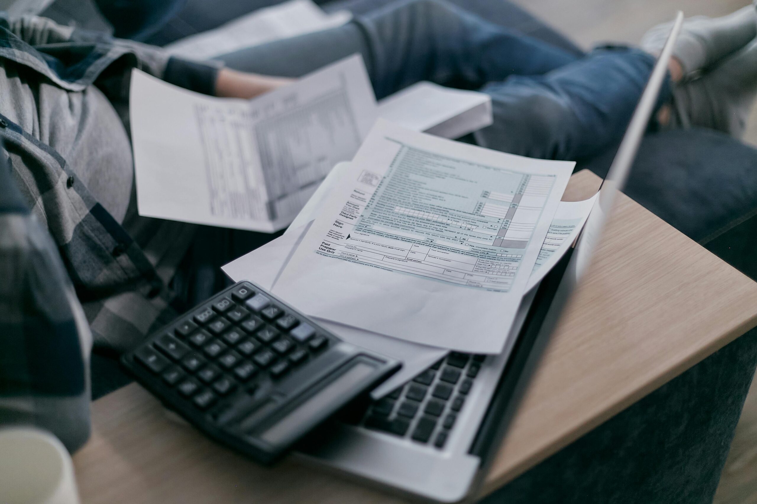 Person working on financial documents with a calculator, showcasing the role of an outsourced accountant.