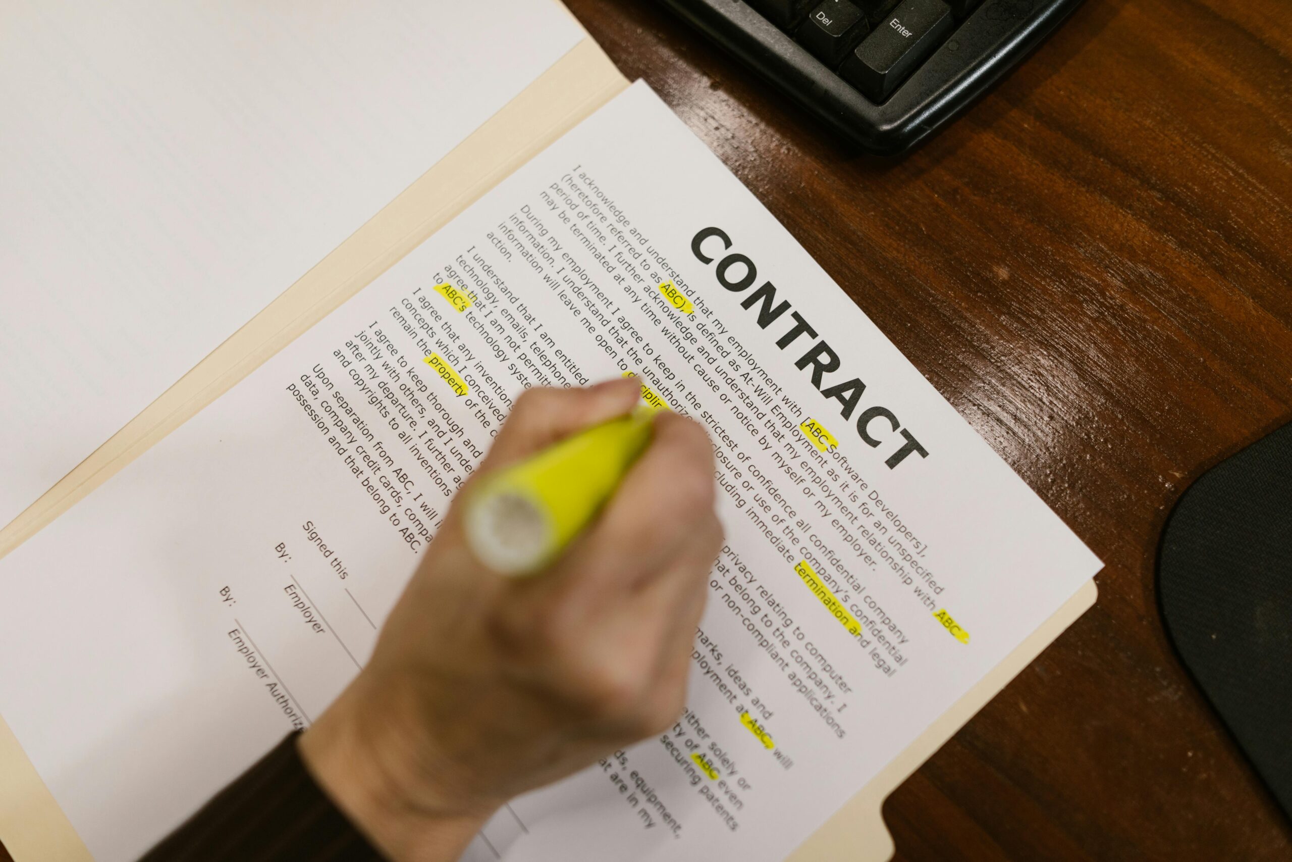 A close-up of a hand highlighting terms on a contract related to how a US company can hire a foreign independent contractor.