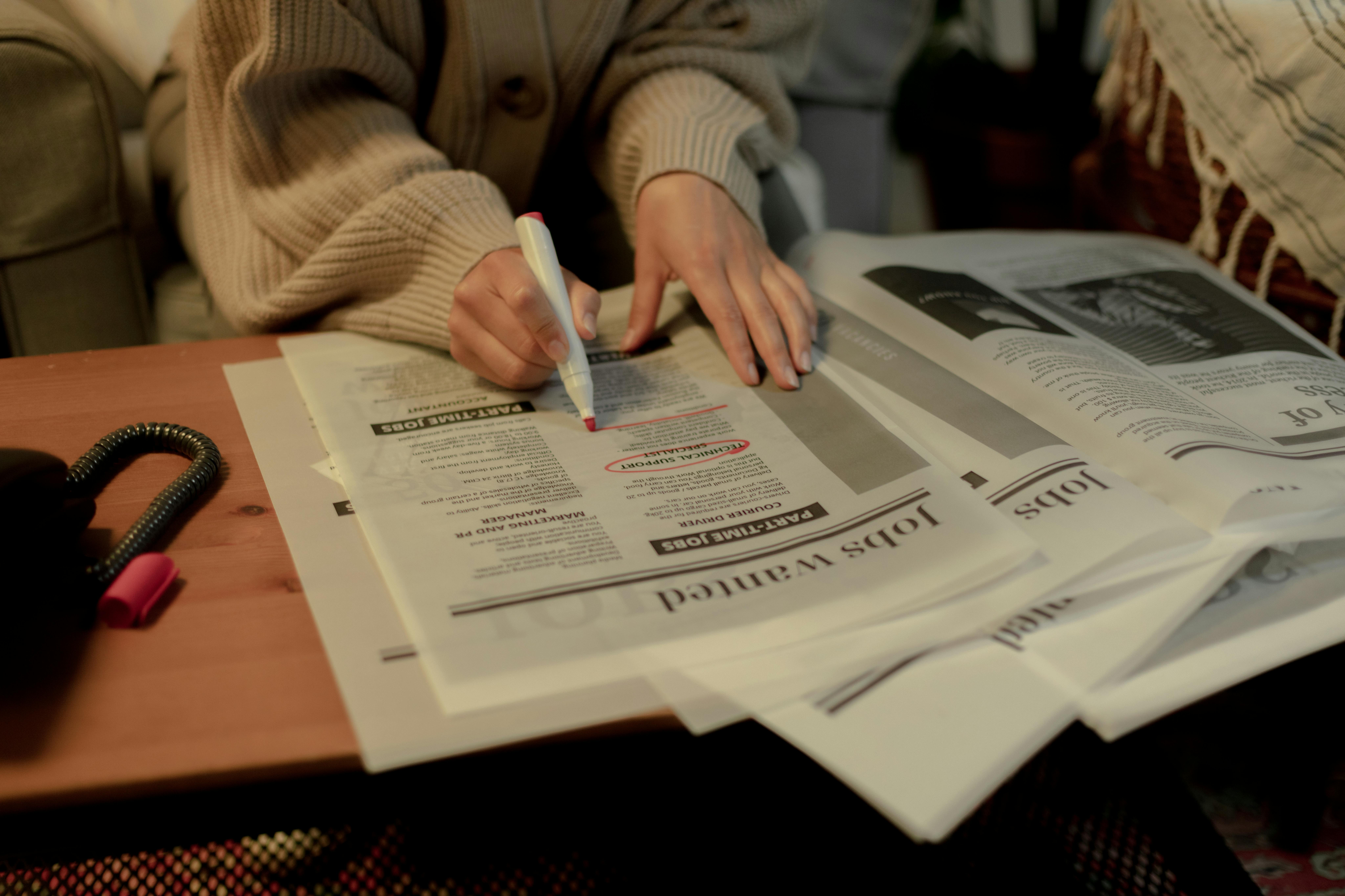 Person highlighting job listings in a newspaper while researching how to hire and pay remote employees in Argentina.