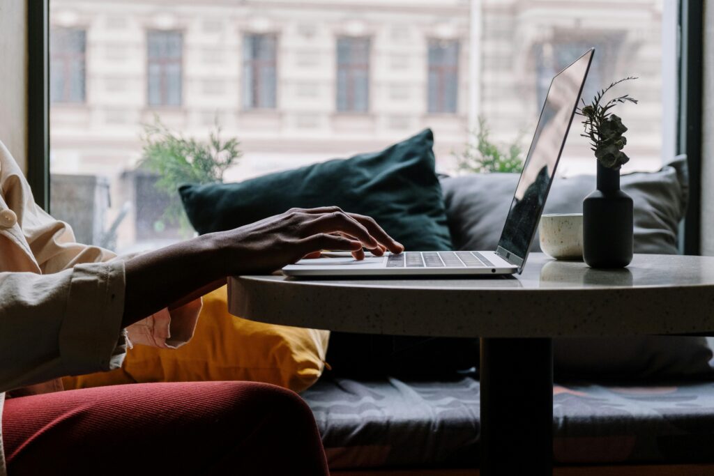 Close-up of a person working on a laptop in a cozy environment, symbolizing the flexibility of outsourced recruiting services.