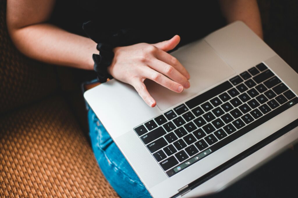 Close-up of a person working on a laptop from a cozy environment, demonstrating the convenience of outsourcing virtual assistant services.