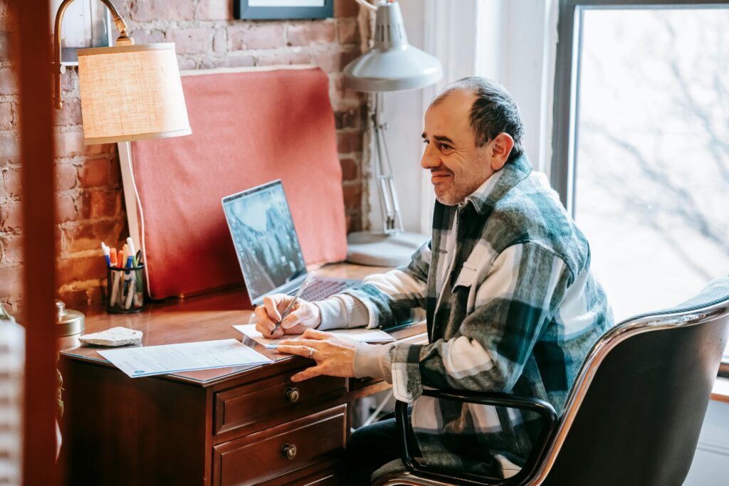 A professional writing notes at their desk while evaluating outsourcing advantages and disadvantages.