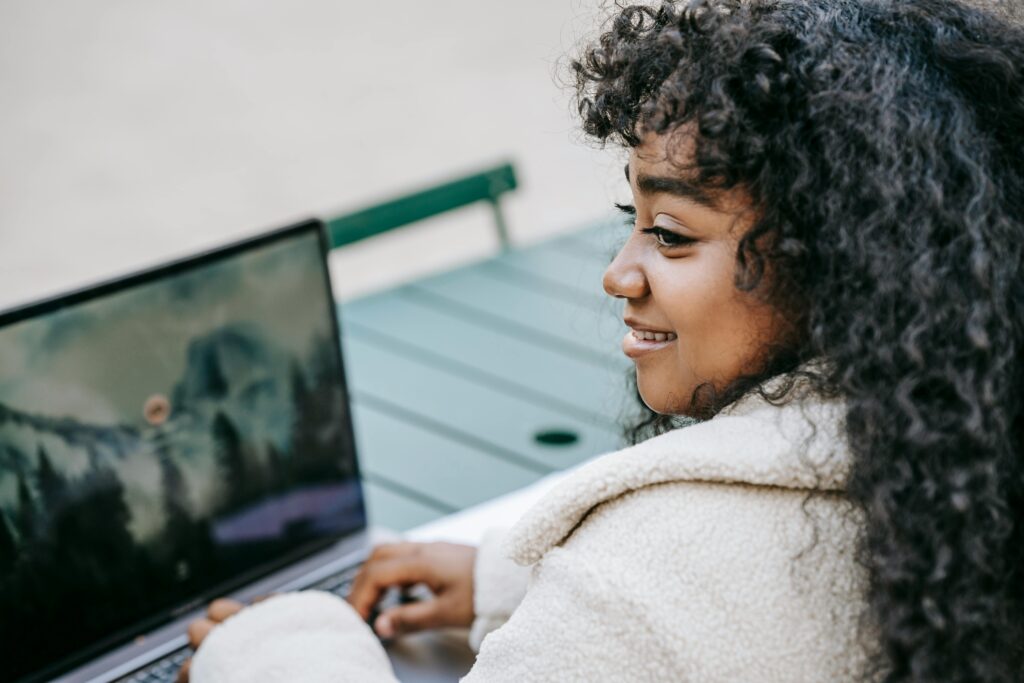 A businesswoman sitting at her desk, smiling while working on a laptop, showcasing the professional assistance of staffing firms near me.