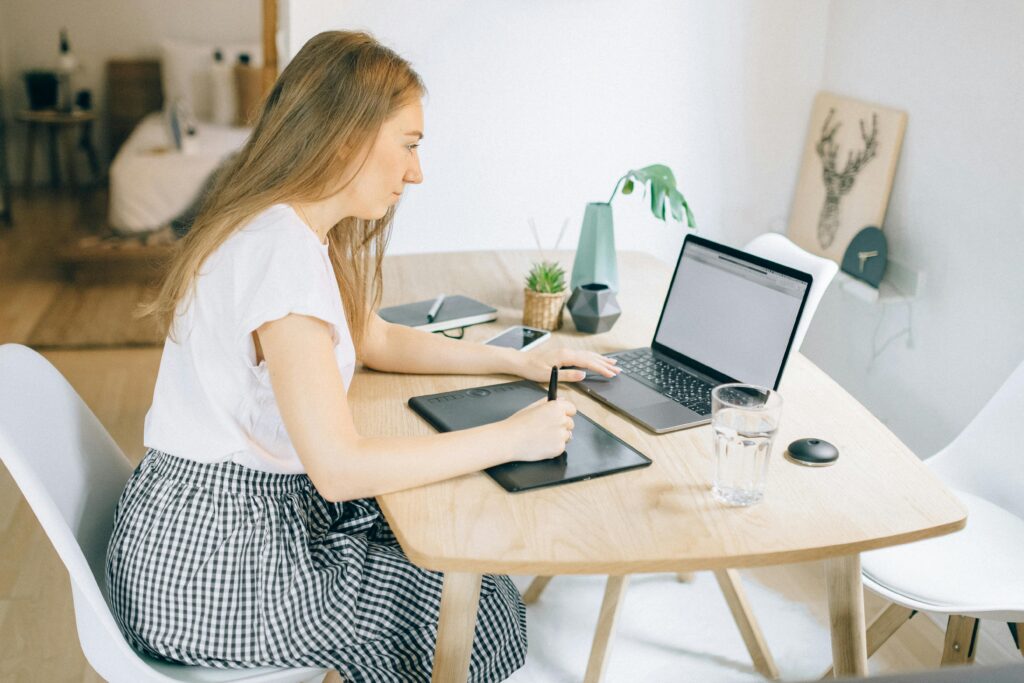A virtual assistant for eCommerce working from home on a tablet and laptop in a cozy environment.