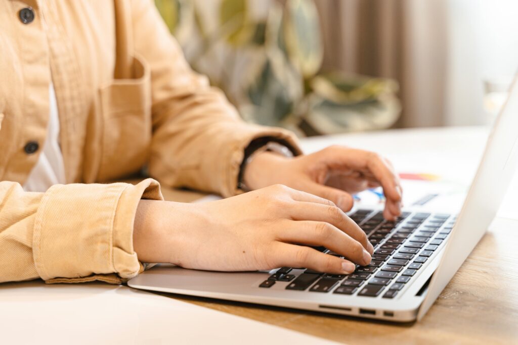 A person at a help desk typing on a laptop, surrounded by green plants and soft lighting, creating a serene workspace.