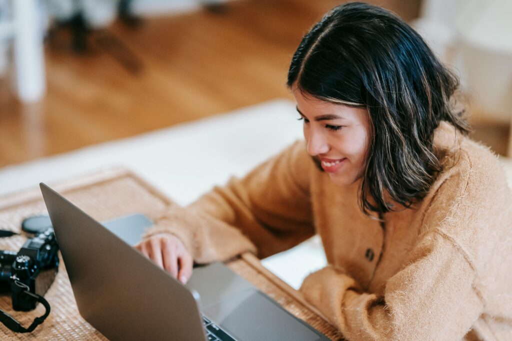 Close-up of hands typing on a laptop while researching outsourcing advantages and disadvantages.