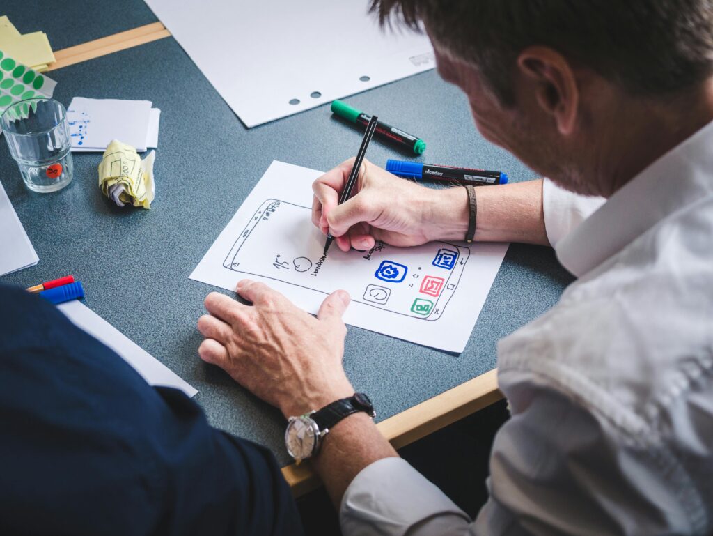 Two individuals collaborating on a UX design sketch, focusing on a UX writer key skills summary.