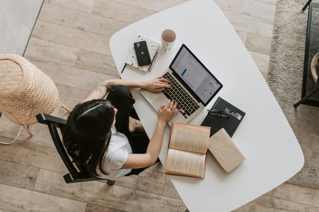 Top view of a desk with a laptop, books, a notebook, and a coffee cup, symbolizing the SEO content strategist key skills summary.