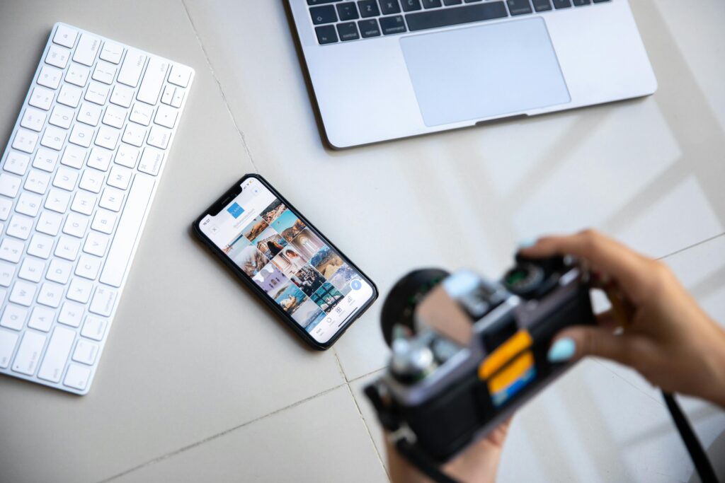 A community manager curating visual content on a smartphone while holding a cam-velascoera, working on digital engagement strategies.