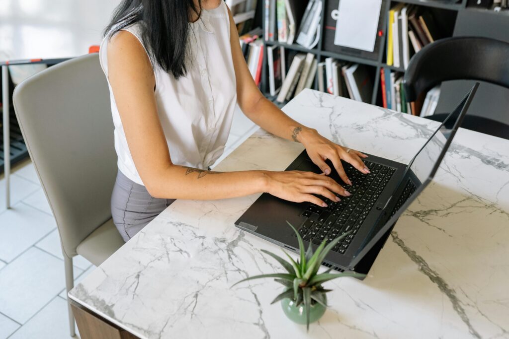 An individual, possibly an executive assistant, typing on a laptop at a desk.