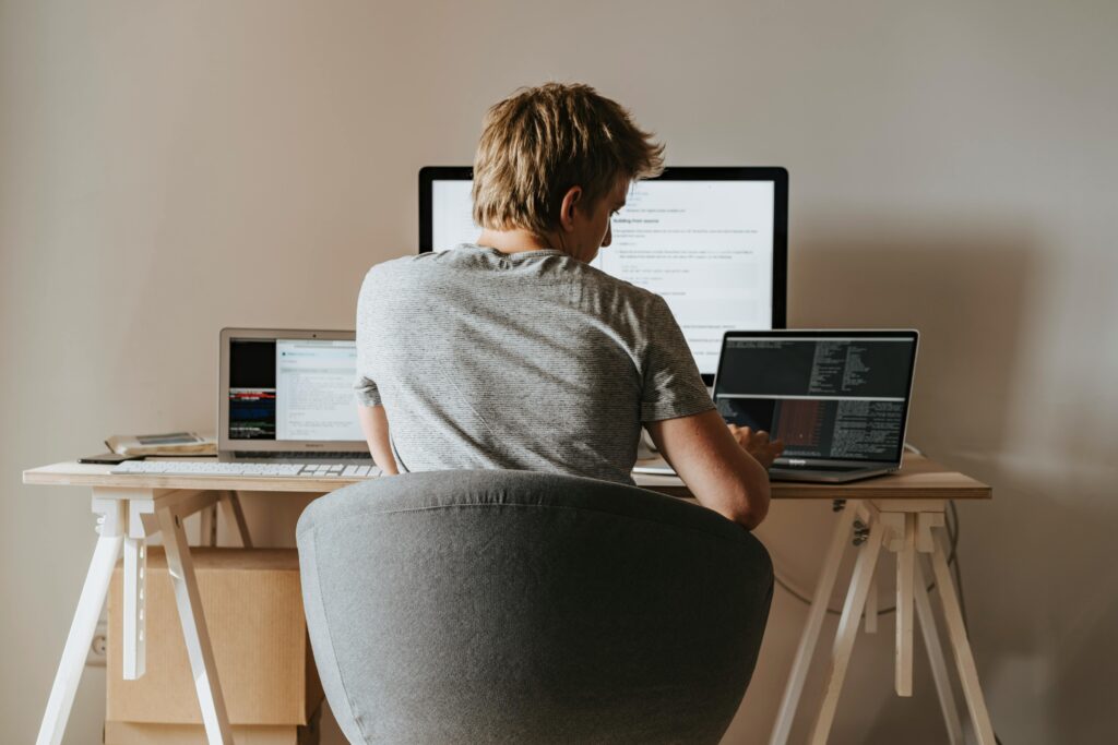 Web designer working from home with multiple monitors displaying code and development interfaces