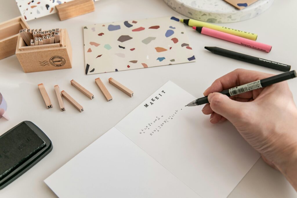 Handwriting and stamps on a desk surrounded by colorful tools and decor, symbolizing the design of a Creative Project Manager Resume Template.