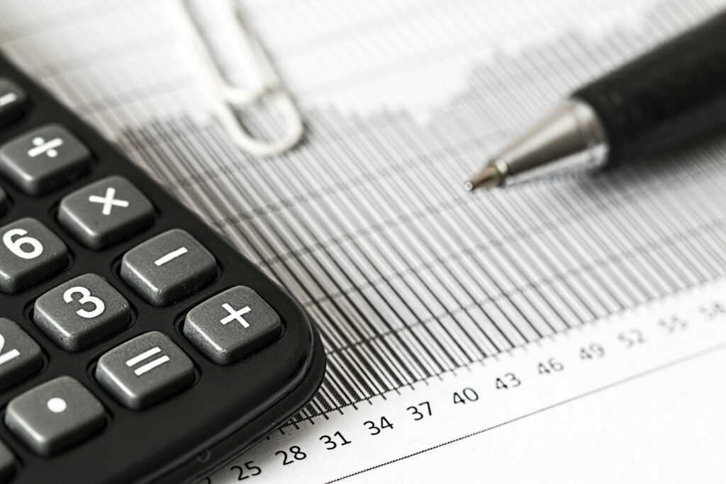 Calculator displaying "TAXES" alongside financial graphs, illustrating the financial considerations for "How to Stay Tax-Compliant When Hiring Offshore Talent" in 2025, considering IRS inflation adjustments.