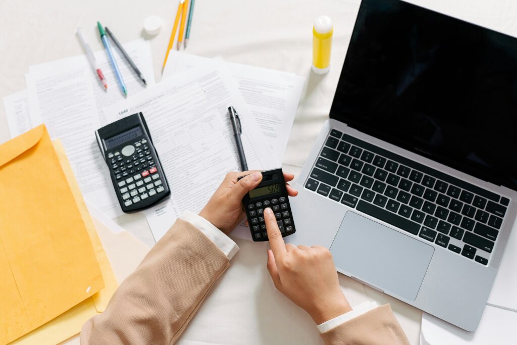 A close-up of a desk with various financial documents, including forms and receipts, along with a black calculator and a pair of eyeglasses, suggesting financial planning or accounting tasks.