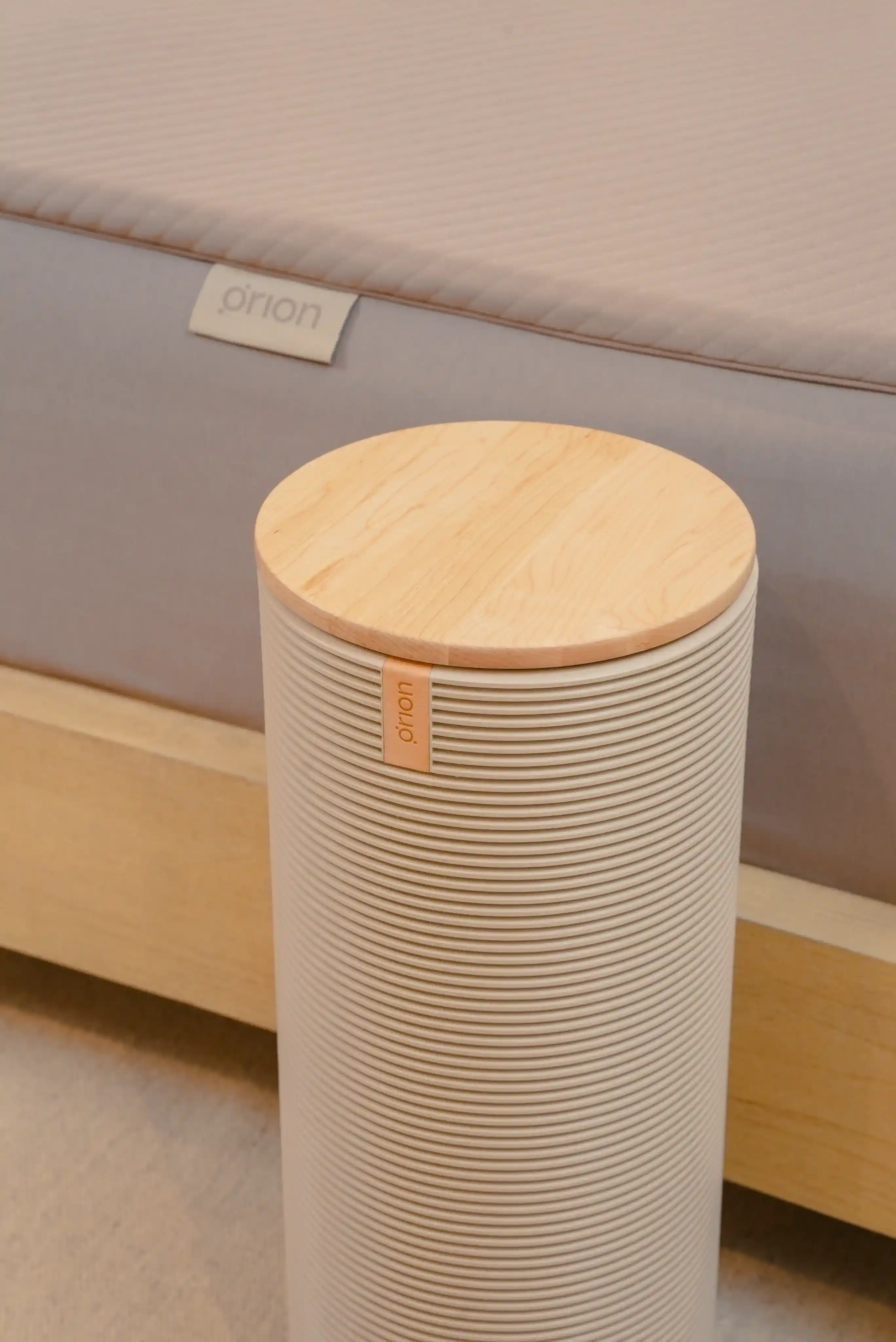 The Orion Control Tower stands in front of a bed with a modern wooden frame. The mattress is covered by the Smart Cover. 