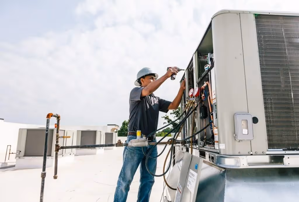 Technician services rooftop HVAC VRF unit.