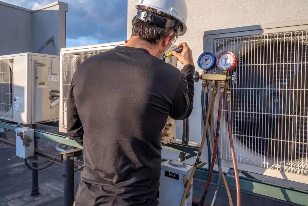 Technician checks rooftop HVAC refrigerant levels.