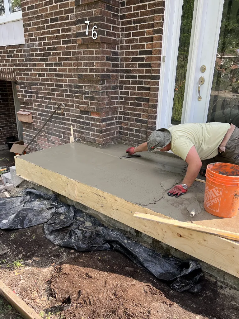 FRONT LINE MASTERS worker applying concrete screed on a porch