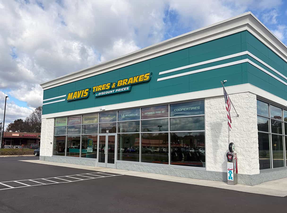 Angled view of the Mavis Tire entrance in Randleman, NC, beside striped parking spaces.