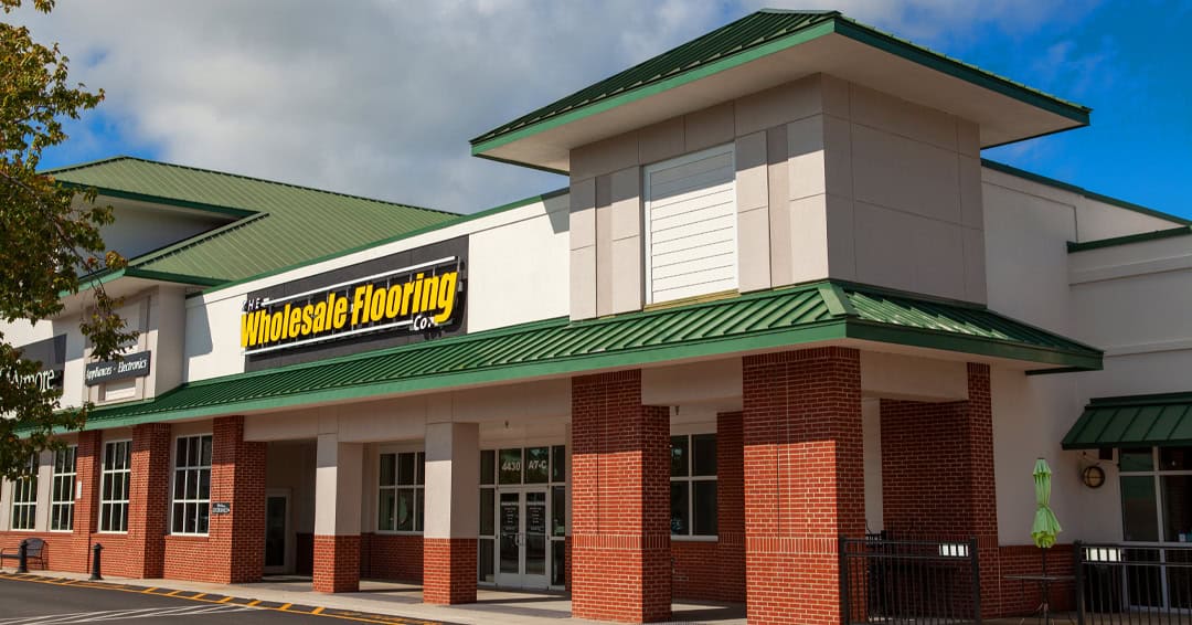 Wholesale Flooring storefront with green roofs and a corner tower in Murrells Inlet, SC.