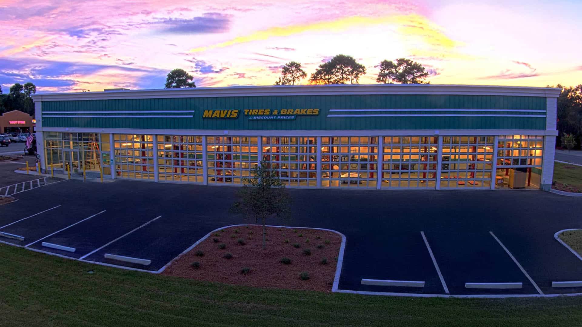 Mavis Tire building and striped parking lot at sunset in Savannah, GA.