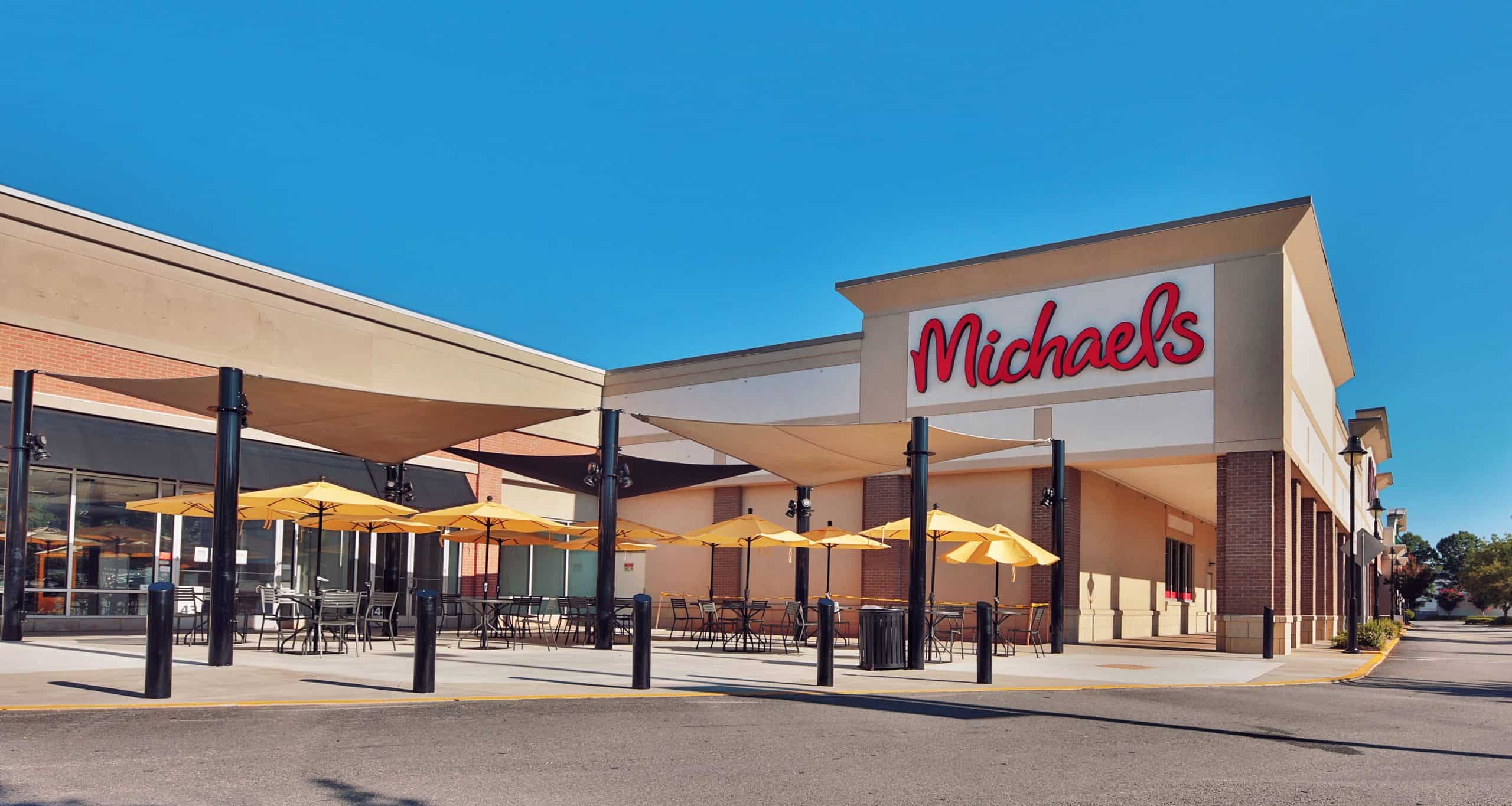 Outdoor tables, yellow umbrellas, and shade sails beside Michaels in Athens, GA.